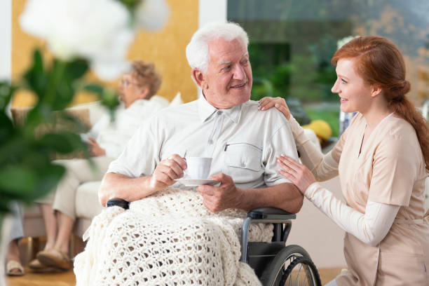 istock Happy paralysed senior man on the wheelchair drinking tea while caregiver supporting him 964234130