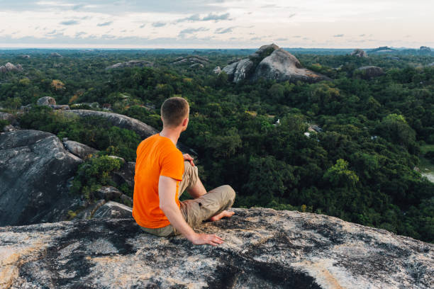 istock tranqul man sitting on the big stone in the forest 964234328