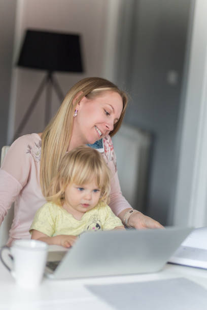 istock Mom works on college assignment while cuddling with infant daughter 964236774