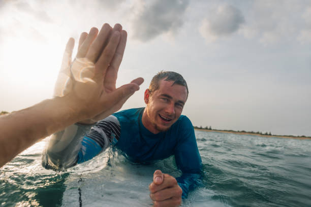 from   first person, give five surfers on the water stock photo