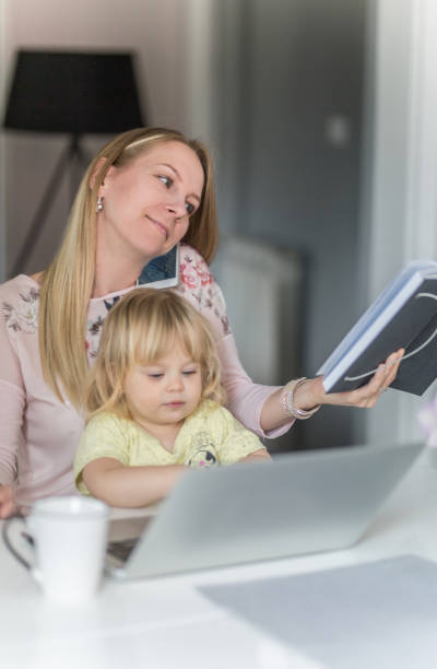 istock Mom works on college assignment while cuddling with infant daughter 964237074
