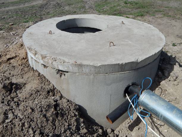 anelli di cemento. pozzo artesiano. l'acqua oscilla da terra attraverso il tubo con l'aiuto di una pompa. - precast foto e immagini stock