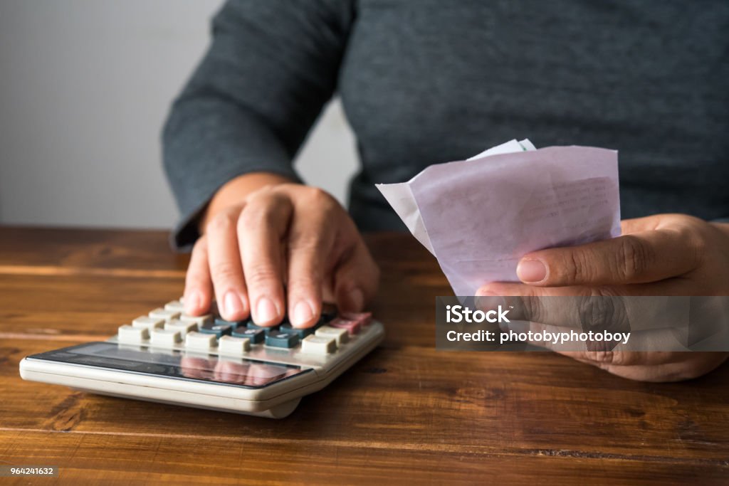 Hand on calculator to calculate cost based on holding bill. Analyzing Stock Photo