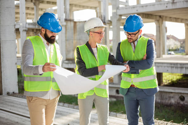 istock Group of architects or business partners discussing floor plans on a construction site 964242222