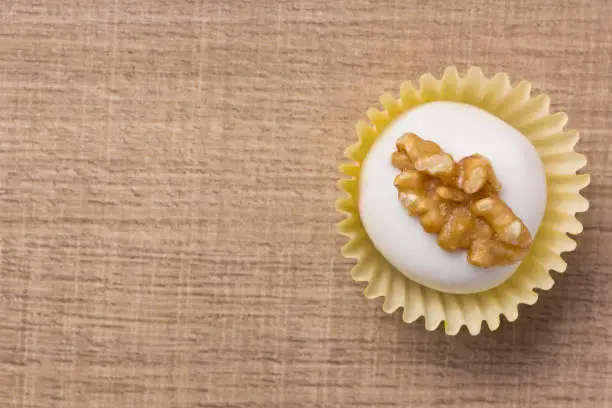 Homemade white chocolate truffle. Known as Camafeu in Brazil. Delicious sweet temptation. Flat lay design of candy ball over wood.