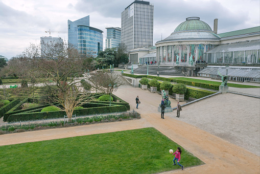 Brussels, Belgium - April 3, 2018: Green area around building Le Botanique with orangery, urban towers, garden and walking people on April 3, 2018. More than 1,200,000 people lives in Brussels