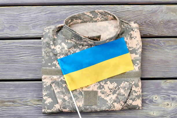 istock Camouflage jacket and ukrainian flag on wood. 964256710
