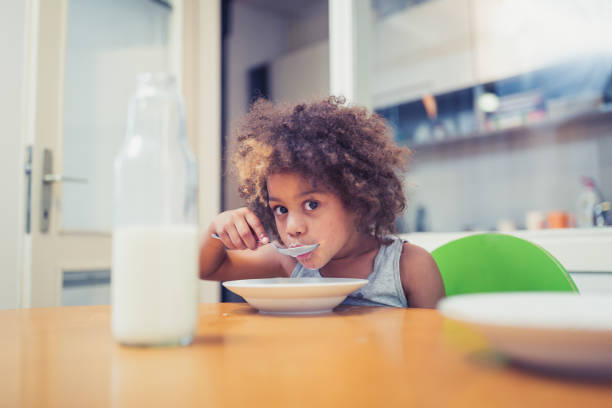 istock Cute mixed - race girl having breakfast at home 964259462