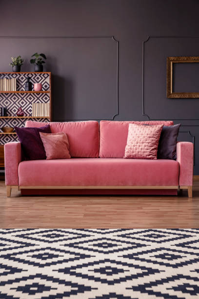 istock Patterned rug in front of a pink sofa with pillows in an elegant living room interior with wall molding and cupboard in the background 964263892