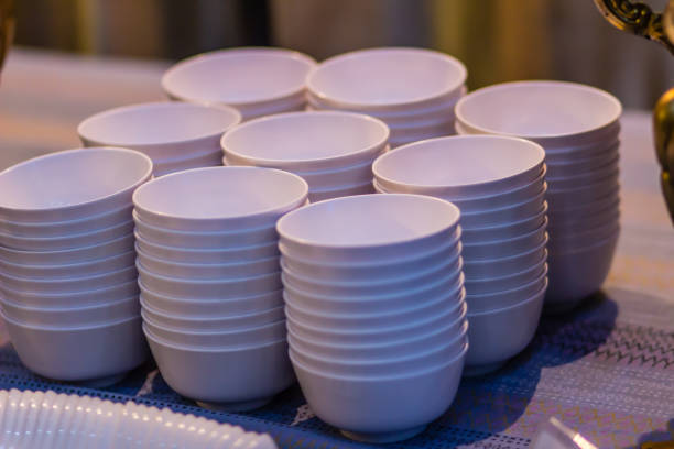 istock Stack of clean white bowl on a table for a buffet in the restaurant. Cleaned white soup or salad bowls in commercial kitchen of restaurant. Pile of clean empty cups on the table prepare for party. 964267302