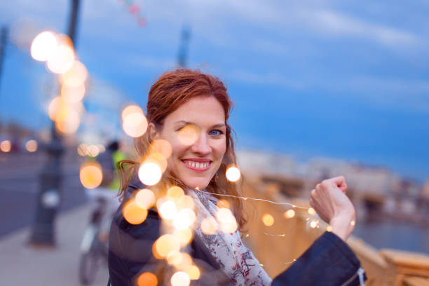 istock Redhead woman pulling garland fairy lights 964267502