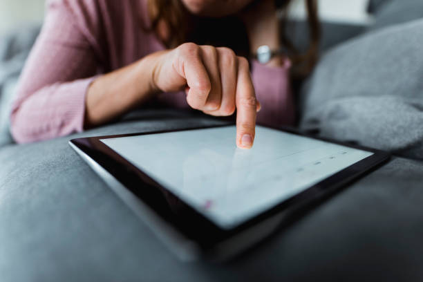 primo posto di una donna che usa tablet digitale sul divano - navigare in internet foto e immagini stock