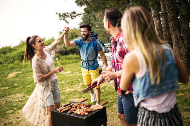 Group of young people preparing and decorating a table outside in a huge garden for a dinner party.