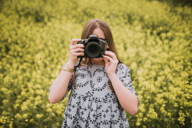 istock Young woman taking a picture with a DSLr camera 964278790