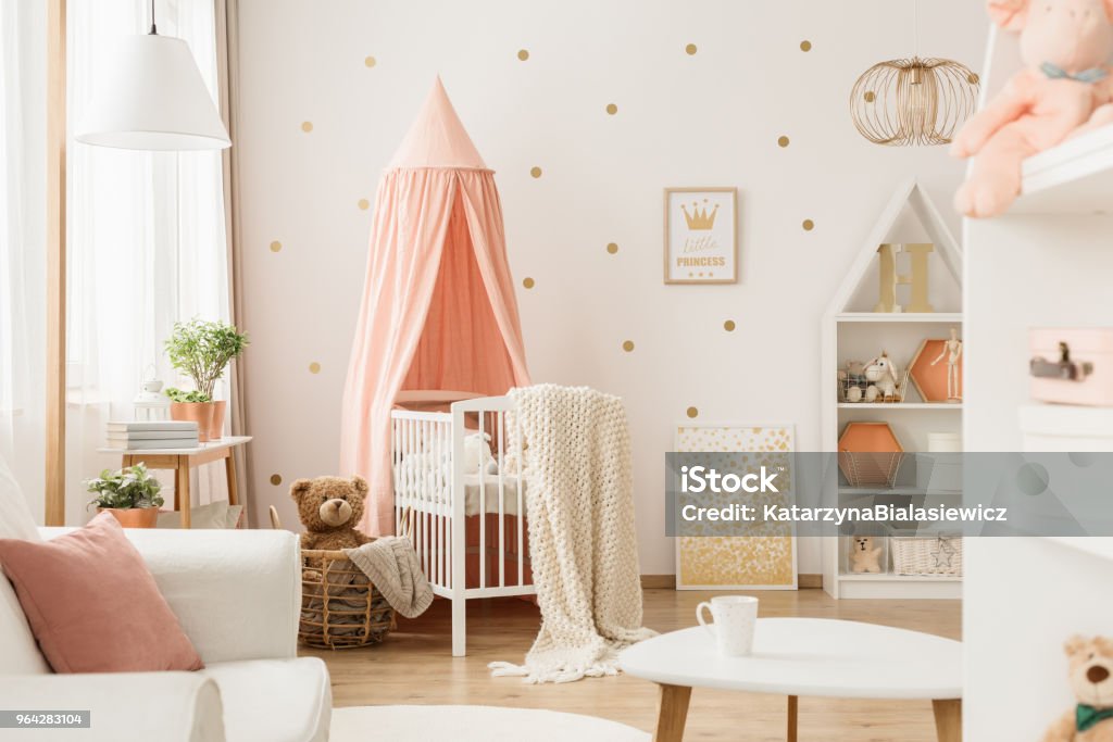 Pink and gold baby's bedroom Pink canopy above cradle in baby's bedroom interior with gold posters and teddy bear in basket Nursery - Bedroom Stock Photo