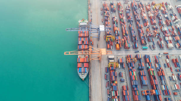 istock Container ship in export and import business and logistics. Shipping cargo to harbor by crane. Water transport International. Aerial view and top view. 964283168