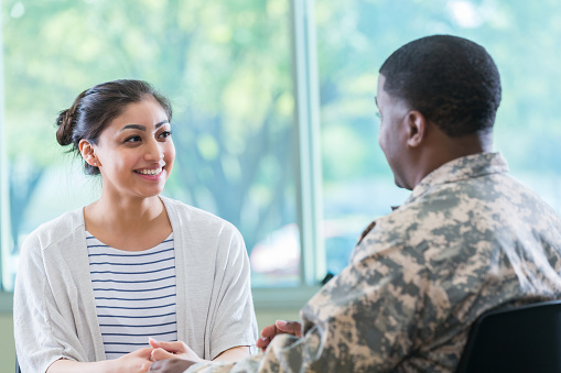 Confident young Hispanic woman talks with an army recruitment officer.