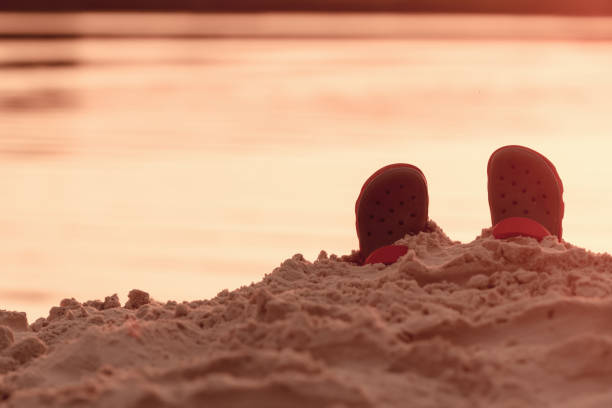 istock Child shoes on sea beach. 964286898