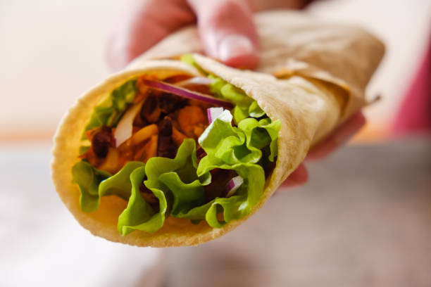 istock Mexican burrito in hand with chicken, pepper and beans 964287260