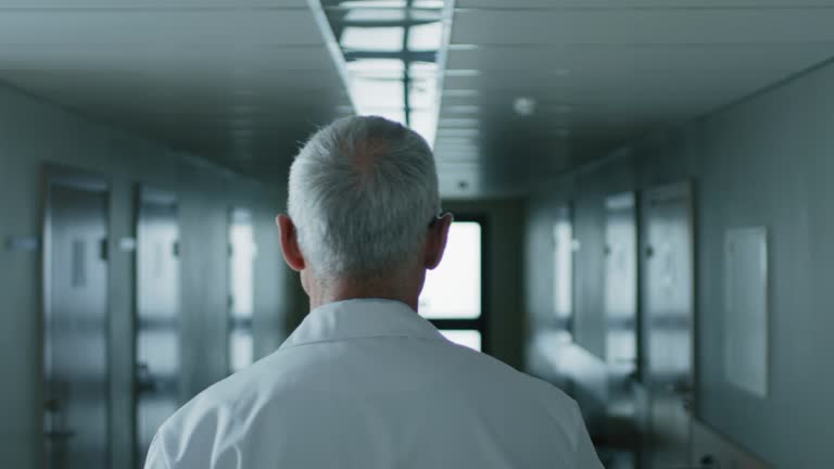 Following Shot of the Professional Male Doctor Walking Through Hospital Hallway. Portrait Footage.