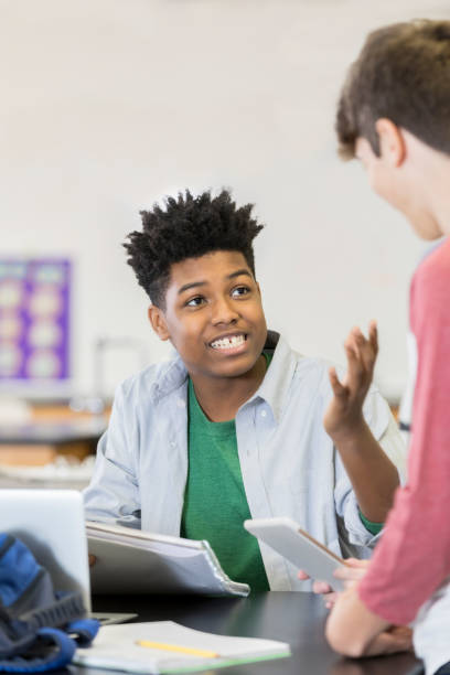 istock Teenage boy talks with a friend in class 964287798