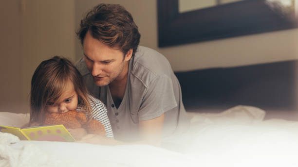 istock Father and daughter reading a story book 964292186