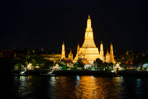 istock Wat Arun temple at night time with glitter light on the water 964292646