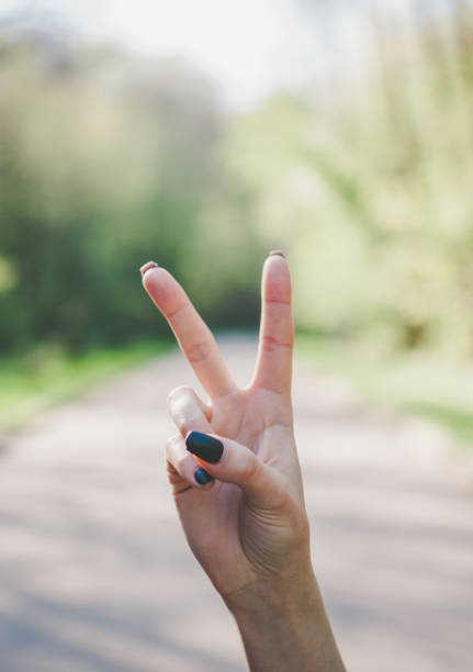 istock Girl making a victory gesture against sunny green background. 964292964