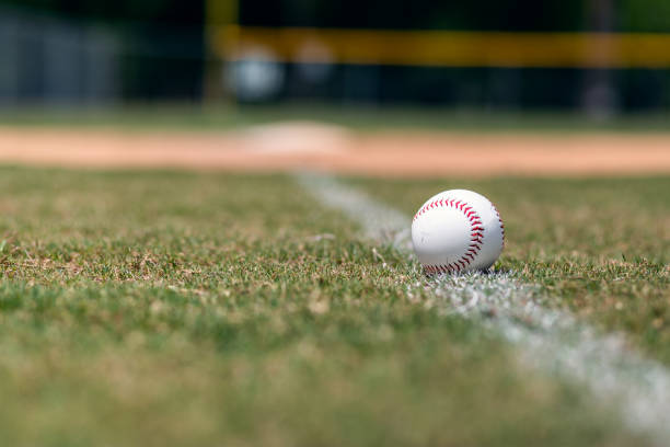 Baseball on foul line Baseball on foul line with base and outfield out of focus in background. baseball diamond photos stock pictures, royalty-free photos & images