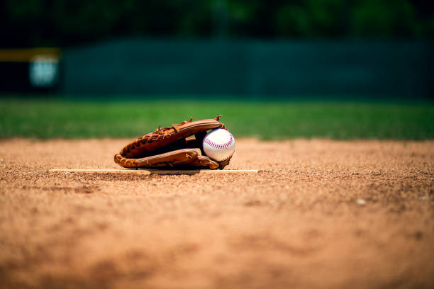 Baseball glove on pitchers mound Baseball on foul line with base and outfield out of focus in background. baseball glove stock pictures, royalty-free photos & images