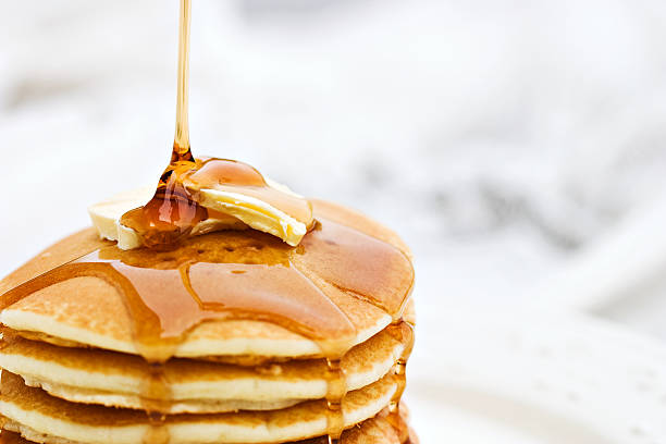 Pancakes Maple syrup pouring onto pancakes. Shallow DOF with focus on syrup and butter.  maple syrup stock pictures, royalty-free photos & images