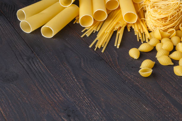 istock Dried mixed pasta on the dark wooden table top view, with copy space 964312946