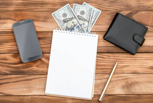 istock Notepad with money, purse and smartphone on the table. Top view. 964318198
