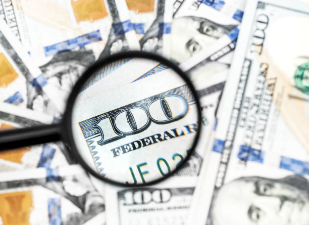 istock One hundred dollar bills under magnifying glass. Business concept. 964318936