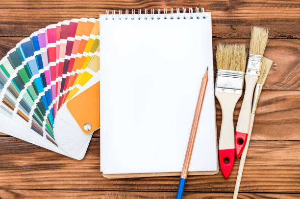 istock Blank notepad with color swatches book and paintbrushes on the table. 964321478