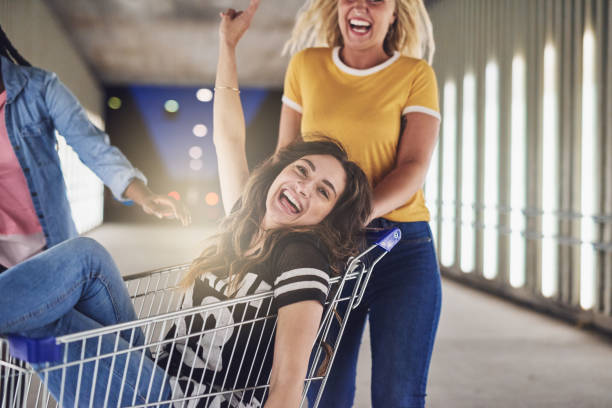 istock Laughing girlfriends playing with a shopping cart at night 964321666