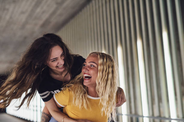 istock Laughing young woman carrying her girlfriend on her back 964322100