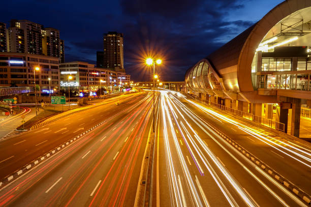 istock Light Trails On Road Amidst Buildings In City At Night 964328982