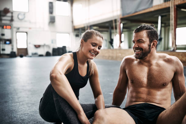 istock Smiling young couple sitting together on a gym floor 964329172