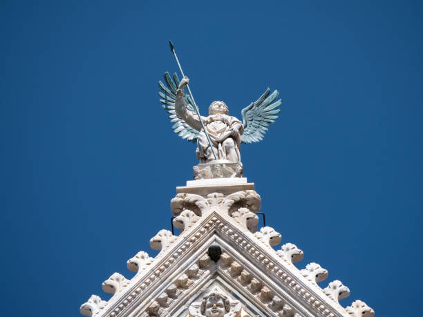 Bronze winged angel on top of the upper facade of the Duomo of Siena