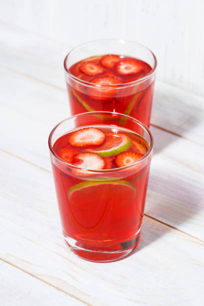 two glasses of strawberry-citrus lemonade on a white background, vertical