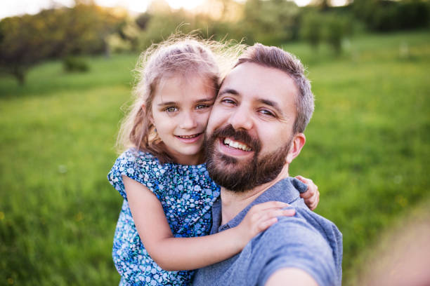 istock Father with a small daughter having fun in spring nature, taking selfie. 964344202