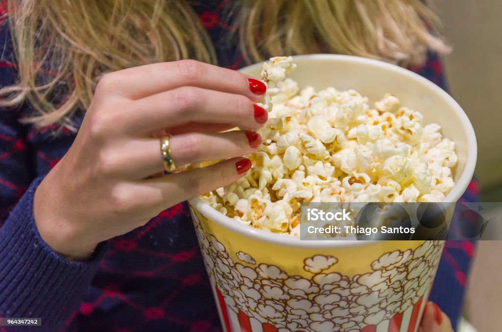 Woman's hand close up, picking up popcorn. Popcorn Stock Photo