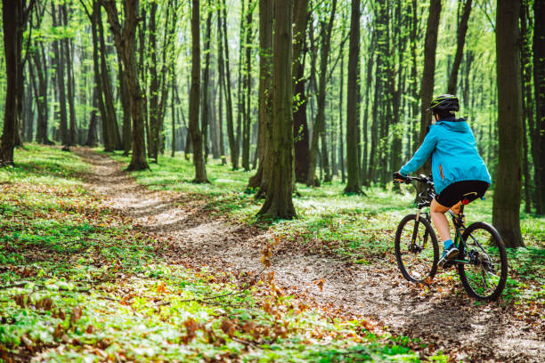 istock young woman ride bicycle in forest by trail 964352286