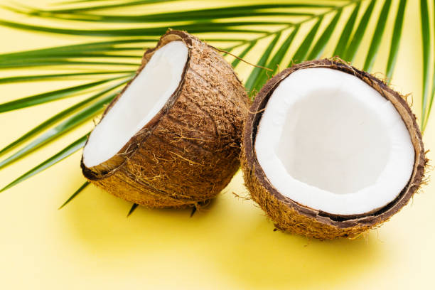 istock Coconut halves and leaves on yellow background 964357652