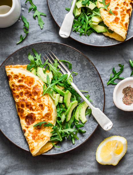 istock Omelette with avocado arugula salad - healthy snack or breakfast on a grey background, top view 964358620