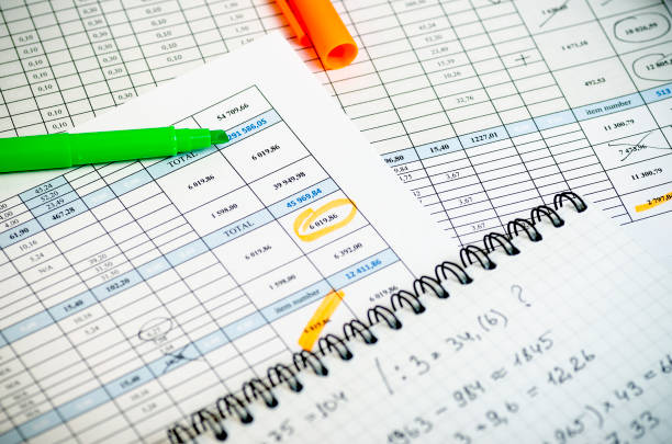 istock Accounting reports in tables, a paper notebook with profit calculations and highlighters 964361618