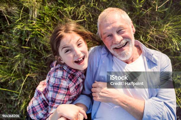 Een Klein Meisje Met Grootvader Buiten In De Natuur Van De Lente Ontspannen Op Het Gras Stockfoto en meer beelden van Bejaard