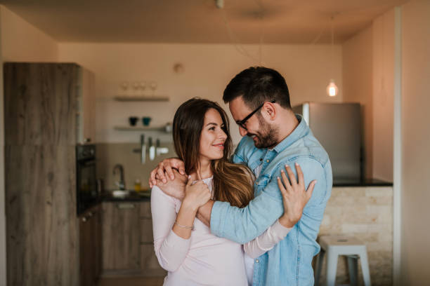 istock Affectionate couple smiling and hugging each other while standing at home. 964372322