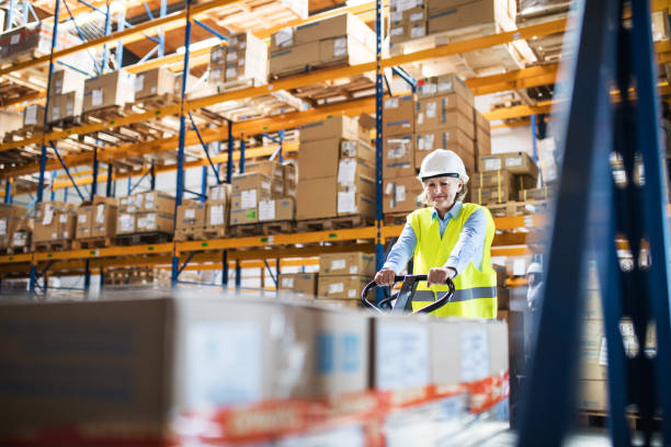 istock A senior woman warehouse worker pulling a pallet truck with boxes. 964380510